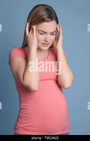 Femme enceinte souffrant de maux de tête sur fond bleu Banque D'Images