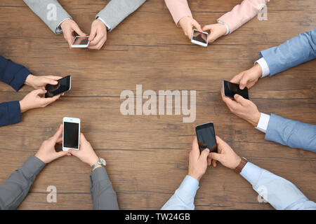 Les gens assis à table et à l'aide de smartphones, vue d'en haut Banque D'Images