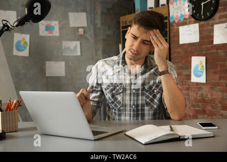 Beau jeune homme souffrant de maux de tête alors que working in office Banque D'Images