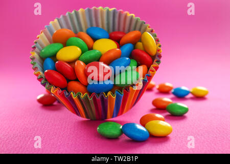 De délicieux bonbons colorés dans la tasse sur un fond de couleur Banque D'Images