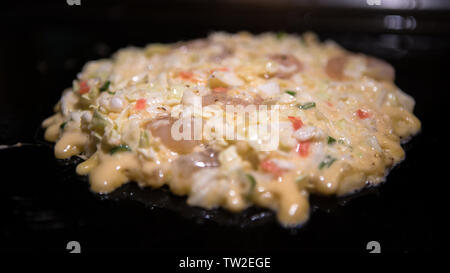 Okonomiyaki nourriture japonaise. Pancake contenant une variété d'ingrédients, la pâte, faite de farine et d'eau, chou râpé, l'oeuf, l'oignon et les fruits de mer. Banque D'Images