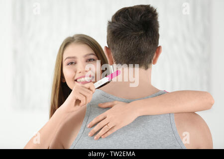 Smiling young woman hugging son mari et la tenue en main test de grossesse Banque D'Images