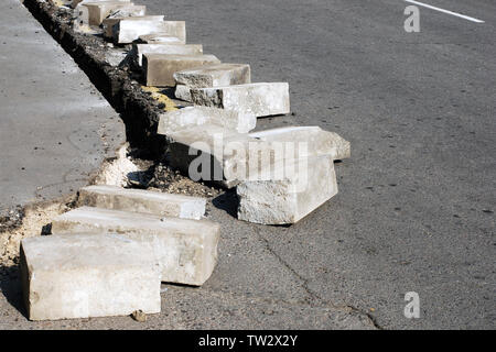 La réparation de bordure en béton sur la route asphaltée, fissuré split des morceaux de béton arrachés sur route Banque D'Images