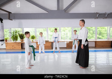 Garçon et formateur. Little Boy wearing kimono blanc devant son entraîneur avant de pratiquer l'aikido Banque D'Images