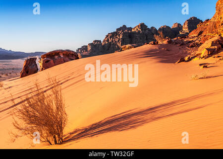 Le soleil se couche dans le désert jordanien à Wadi Rum ou la vallée de la Lune. Banque D'Images