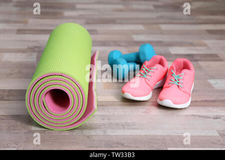 Tapis de yoga avec des baskets et les haltères sur le plancher Banque D'Images