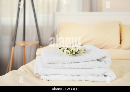 Pile de serviettes et de fleurs sur le lit dans la chambre d'hôtel Banque D'Images