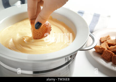 Femme trempant du pain dans la plaque avec la fondue au fromage, gros plan Banque D'Images