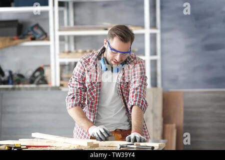 Ponçage Carpenter planche en bois sur la table dans l'atelier d'éclairage Banque D'Images