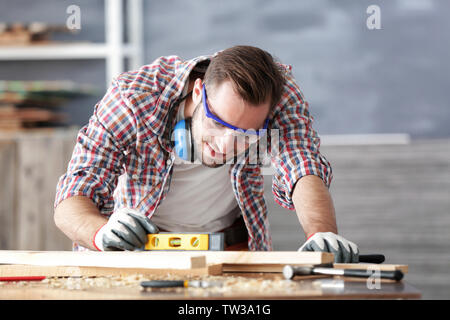 Jeune menuisier travaillant avec niveau dans light shop Banque D'Images