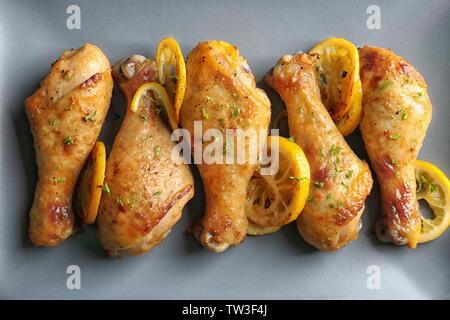 Pilons de poulet rôti délicieux avec du citron sur la plaque, gros plan Banque D'Images