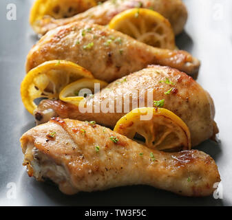 Pilons de poulet rôti délicieux avec du citron sur la plaque, gros plan Banque D'Images