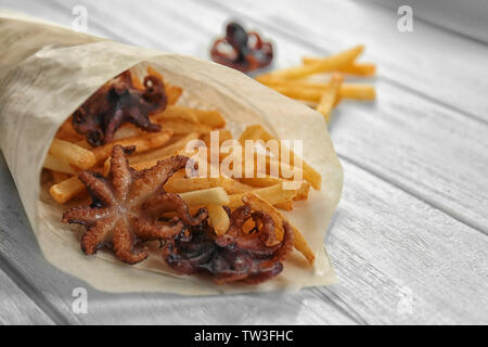 Sac de parchemin avec de délicieux baby octopus et french fries on table Banque D'Images