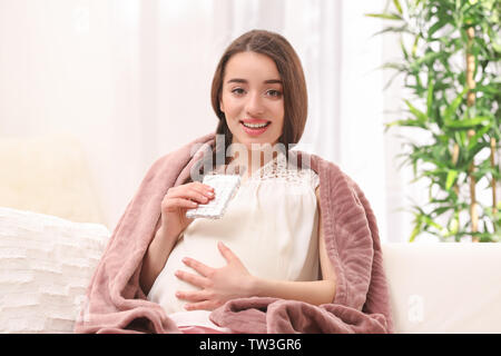 Jeune femme enceinte de manger du chocolat à la maison Banque D'Images