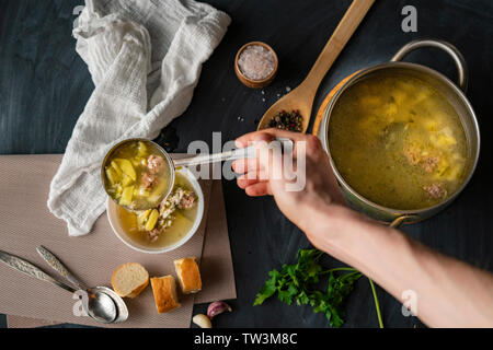 Par ailleurs chefs verser de la soupe dans un bol vide blanc, la préparation des aliments Banque D'Images