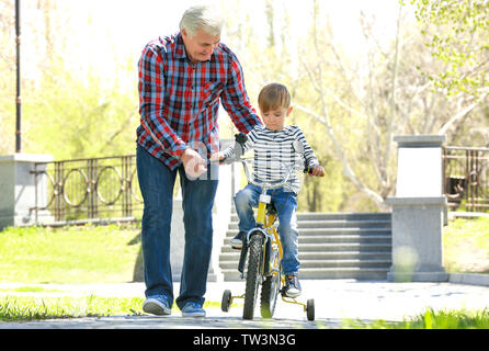 Cute little boy riding sur location et de son grand-père dans la région de Spring Park Banque D'Images