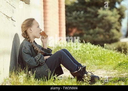 Pauvre petit girl eating bread outdoors Banque D'Images