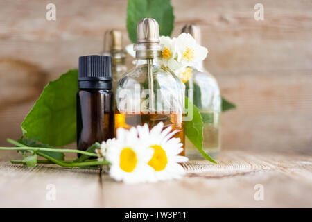 L'huile essentielle de Parfum flacons en verre avec aromatiques fleurs close up sur le vieux fond de bois. L'aromathérapie, spa, bien-être, relaxation, massage aux herbes et moi Banque D'Images