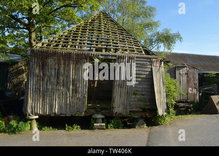 Vieille ferme grain store sur staddle.pierres et bois de construction en tôle ondulée. Dalles plafond enlevé aux fins de réutilisation et de faire tenir ensemble avec de la corde.old elle à roues Banque D'Images