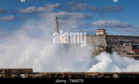 De grosses vagues frappant le Malecon sea wall à La Havane avec la forteresse El Morror et derrière le phare. Banque D'Images