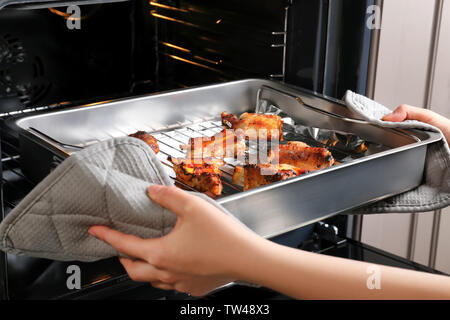 Jeune femme en tenant la plaque de cuisson avec des côtes de porc délicieux hors du four Banque D'Images