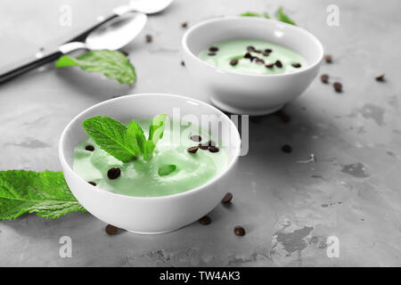 Délicieuse menthe avec bols de crème glacée aux pépites de chocolat et les feuilles fraîches sur la table gris Banque D'Images