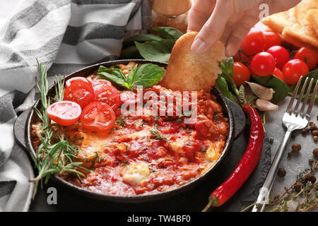 Femme trempant le pain en oeufs dans le purgatoire sur table Banque D'Images