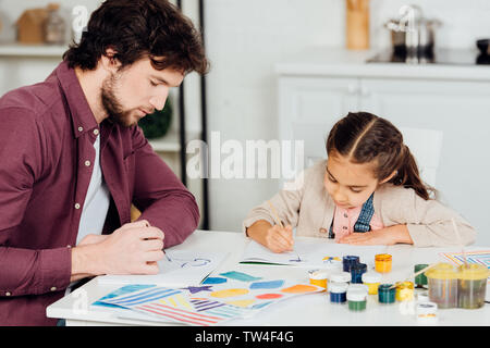 Beau père et fille mignonne avec dessin de pinceaux à la maison Banque D'Images