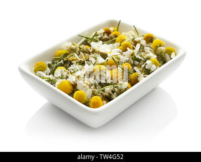 Bol avec fleurs de camomille séchées sur fond blanc Banque D'Images