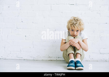 Contrarié preteen boy sitting on floor at home Banque D'Images