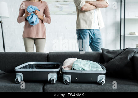 Portrait de l'homme et de la femme debout près de valise à vêtements sur canapé Banque D'Images