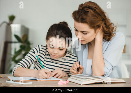 Jolie femme fille faisant le travail scolaire concentré aidant à la maison Banque D'Images