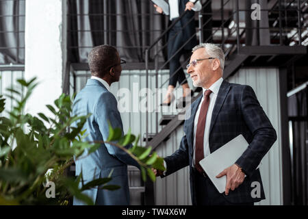 Low angle view of businessman shaking hands with african american partner Banque D'Images