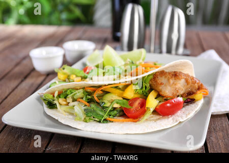 Fish Taco délicieux servi sur plaque blanche sur table en bois Banque D'Images