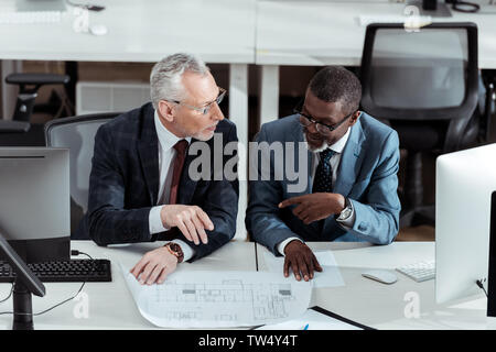 Vue de dessus d'affaires multiculturelles de parler près de blueprints in office Banque D'Images