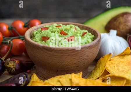 Guacamole au bol en bois avec des croustilles et des ingrédients Banque D'Images