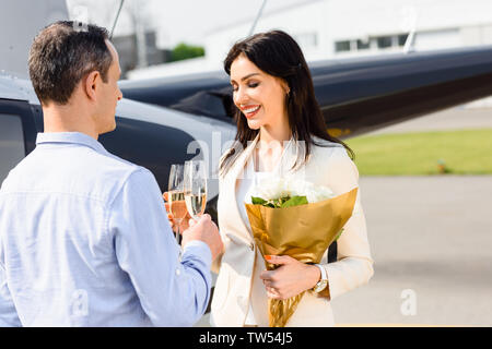 Mari et femme clinking champagne glasses on date romantique près de l'hélicoptère Banque D'Images