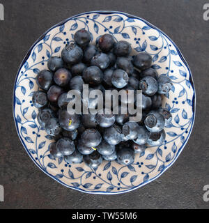 Bleuets frais cueillis sur un blanc avec un motif bleu dans un environnement de cuisine clair et lumineux avec un fond sombre. Banque D'Images