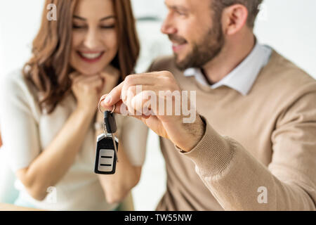 Focus sélectif de handsome man holding clé de voiture et à la recherche à happy brunette woman Banque D'Images