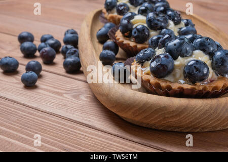 Tartelette aux myrtilles trois sur une plaque de bois sur la table, myrtille, fruits, coquillages cuits avec cupcake blueberry. Banque D'Images