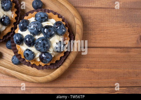 Tartelette aux myrtilles sur une plaque de bois sur la table, myrtille, fruits cuits, shell avec cupcake blueberry. Whortleberry frais Banque D'Images