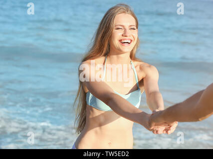 Happy young woman holding part de son petit ami sur mer plage Banque D'Images