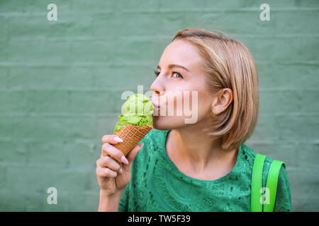 Young happy woman in green hippie robe dentelle la consommation de crème glacée sur un fond de couleur Banque D'Images