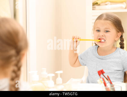 Cute little girl se brosser les dents dans la salle de bains Banque D'Images