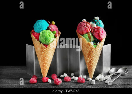La composition avec de la crème glacée, de bonbons et de framboises sur fond noir Banque D'Images