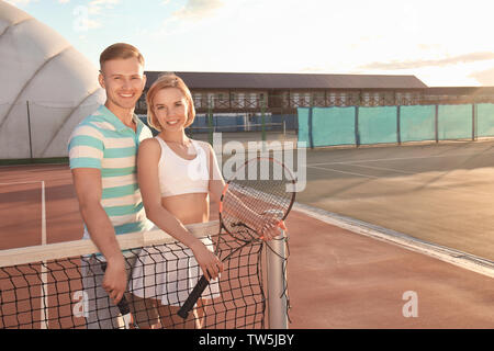 Jeune couple debout sur un court de tennis Banque D'Images