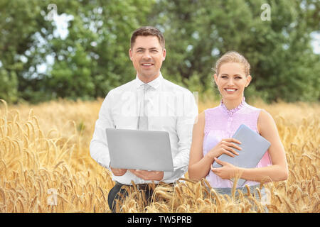 Deux agronomes avec ordinateur portable et tablette en champ de blé Banque D'Images