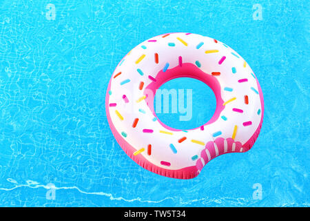 Donut gonflable coloré en bleu piscine Banque D'Images