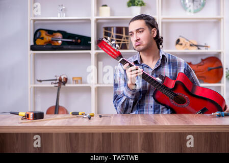 Beau jeune réparateur réparation guitare Banque D'Images