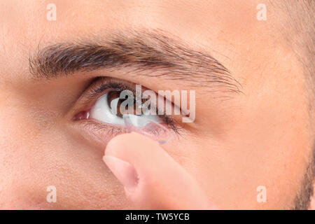 Young man putting contact lens, gros plan Banque D'Images